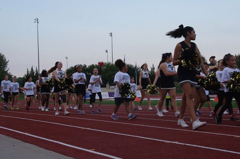 The Cheerleaders and kids walk the track during pre game. 