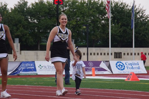 Kiera Beatty, junior cheerleader, walks with a kid around the track 