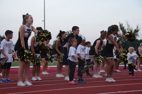 The Cheerleaders cheer with the kids on the sidelines 