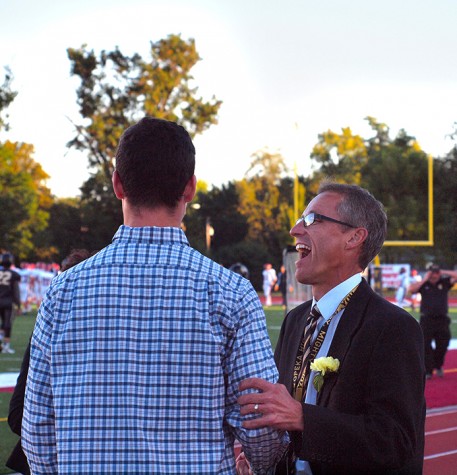 Associate Principal Robert Hays chats it up on the sidelines with 2014 Homecoming King Joel Long.