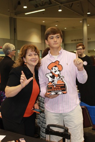 Tristan Weichert, junior, and an OSU (Oklahoma State University)  administrator are "guns up" for the Cow Pokes at the Kansas & Career Fair at the Kansas Expocenter.