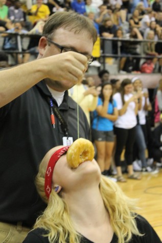 Coach Nelson feeding Emma Shaw a doughnut in the doughnut eating contest