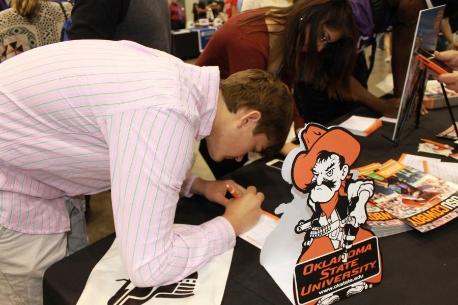 Tristan Weichert, junior, fills out paperwork at the Oklahoma State University booth during the College & Career Fair at the Kansas Expocenter.