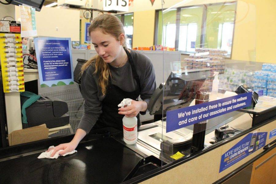 Finishing the last bit on the conveyor belt, Mary McGuire prepares to then sanitize the glass screen and bar code scanner.